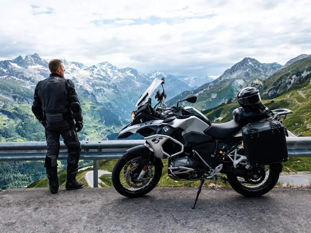 Motocykl BMW R 1300 GS Adventure zaparkowany na górskiej serpentynie, jeździec podziwia alpejski krajobraz w tle