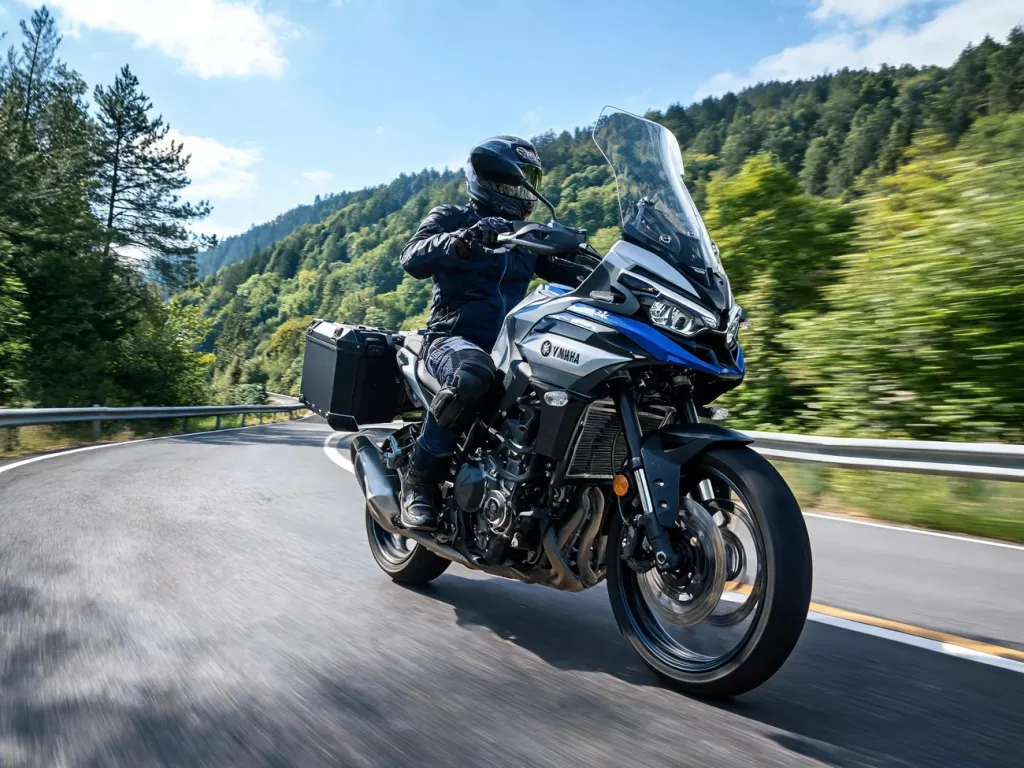 Yamaha Tracer 9 w zakręcie na górskiej drodze, motocyklista w turystycznym stroju, dynamiczna jazda w słoneczny dzień