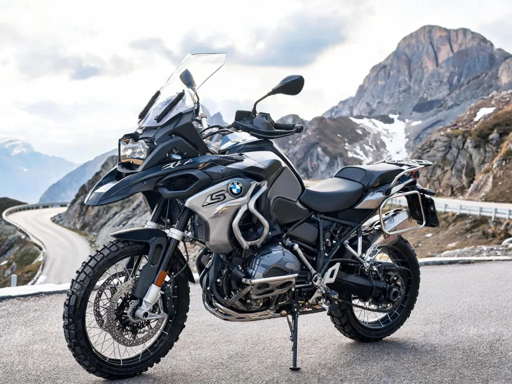 BMW R 1300 GS zaparkowany na górskiej przełęczy, podkreślone silnik, koła i owiewka na tle krętej, wysokogórskiej drogi
