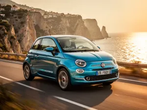 Nowoczesny Fiat Panda jadący malowniczą nadmorską drogą w blasku zachodzącego słońca.
